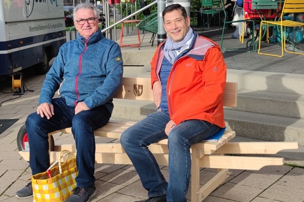 v.l.n.r.: Marcel Tritschler sitzt neben B&uuml;rgermeister Markus Hollemann auf dem Schw&auml;tzb&auml;nkle im Kohlerhof