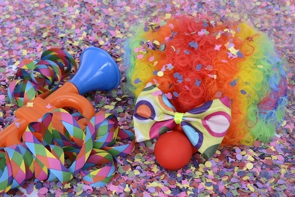 Buntes Konfetti, rote Lockenper&uuml;cke, Fliege, Luftschlangen, Clownnase und Spielzeug Trompete